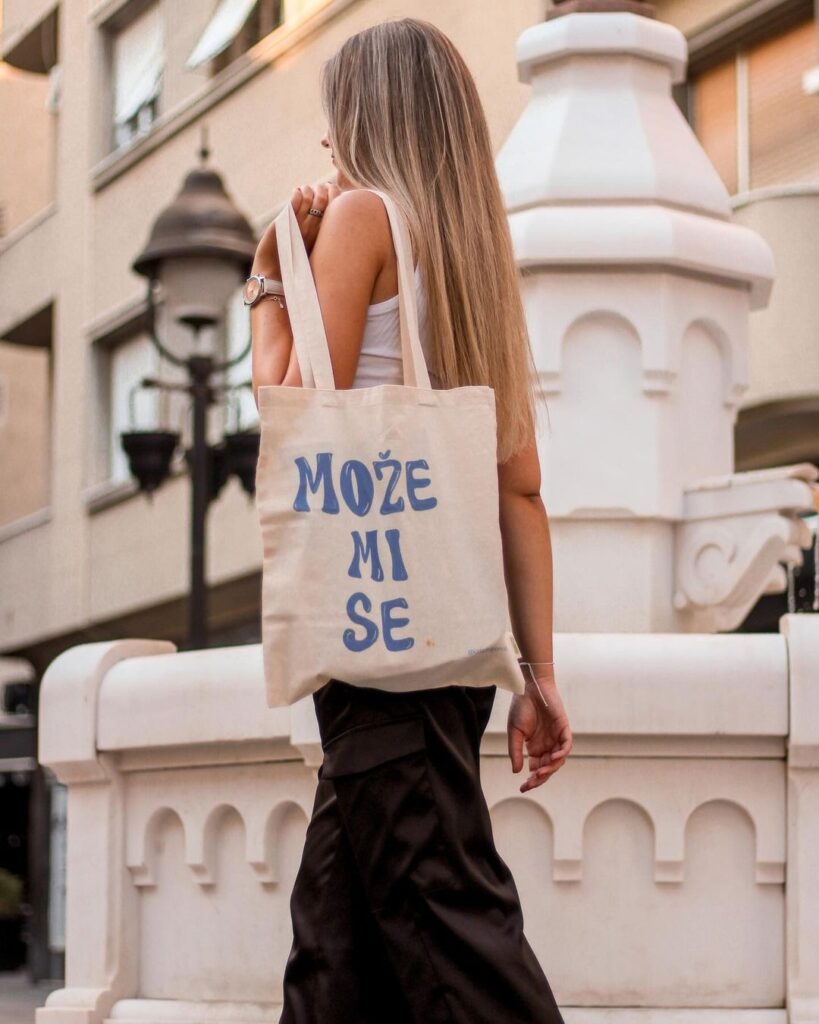 „Može mi se" ceger sa plavim slovima i bež podlogom, devojka ga drži