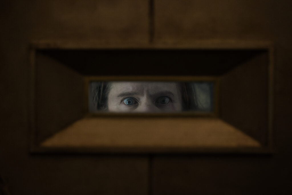 Žena gleda kroz otvor u seriji Silo — sličnoj seriji The Walking Dead